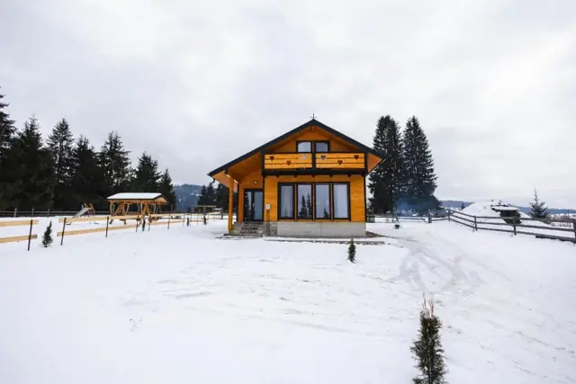 Cabana Almora iarna, înconjurată de zăpadă și brazi